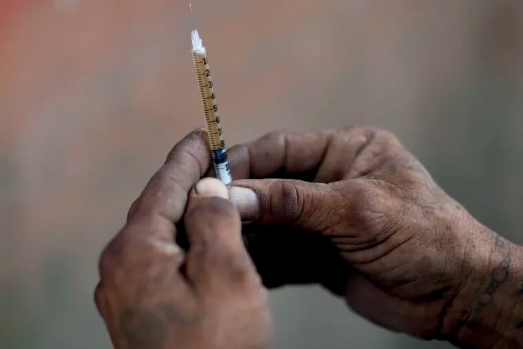 In this Dec. 14, 2018 photo, a heroin addict prepares a dose for himself, in an area where heroine uses shoot up behind an abandoned home in Humacao, Puerto Rico. An opioid problem is growing in Puerto Rico even as the U.S. territory struggles to cope with an economic crisis and the devastation caused by Hurricane Maria. (AP Photo/Carlos Giusti)