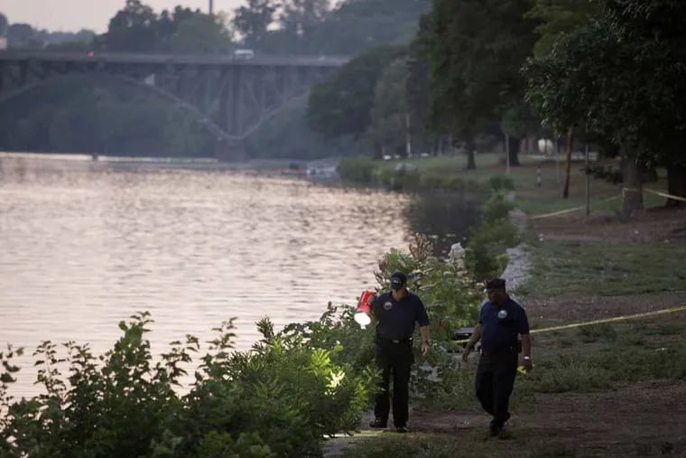 Philadelphia police investigate along the Schuylkill River in August 2014, after the bodies of brothers Viet and Vu Huynh were found stabbed and sunk with buckets of cement. A third man, Tan Voong, survived what he said was an abduction.
