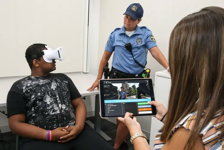 At the Roberts Center for Pediatric Research, Skylar Armstrong, 17, is learning how to interact with police via Floreo, a virtual reality device. 17th district police officer Linda Nagle watches with CHOP's Ashley Zitter, Clinical Research Assistant with the iPad.Wednesday, July 17, 2019