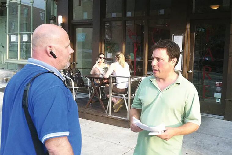 Streets Department inspector Jim Gartland (left) has a conversation about compliance with Andrew Siegel, the owner of Fare at 21st and Corinthian streets. Siegel was written up for not having a current sidewalk café license.