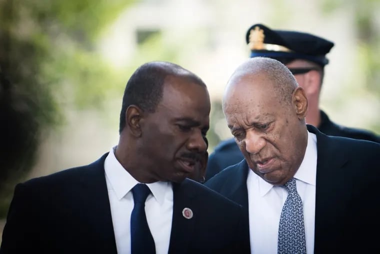 Bill Cosby, speaking with comedian Lewis Dix, walks toward the entrance to the Montgomery County Courthouse.