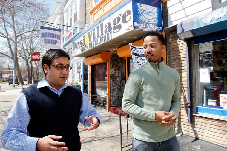 Restaurant owner Sourabh Tolasaria (left) and Algernong Allen, a community organizer, walk along Baltimore Avenue.