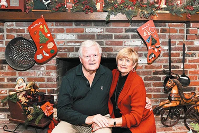 Michael and Mary Woolley of Haddonfield sitting in front of their fireplace decorated for Christmas. (Sharon Gekoski-Kimmel / Staff Photographer)