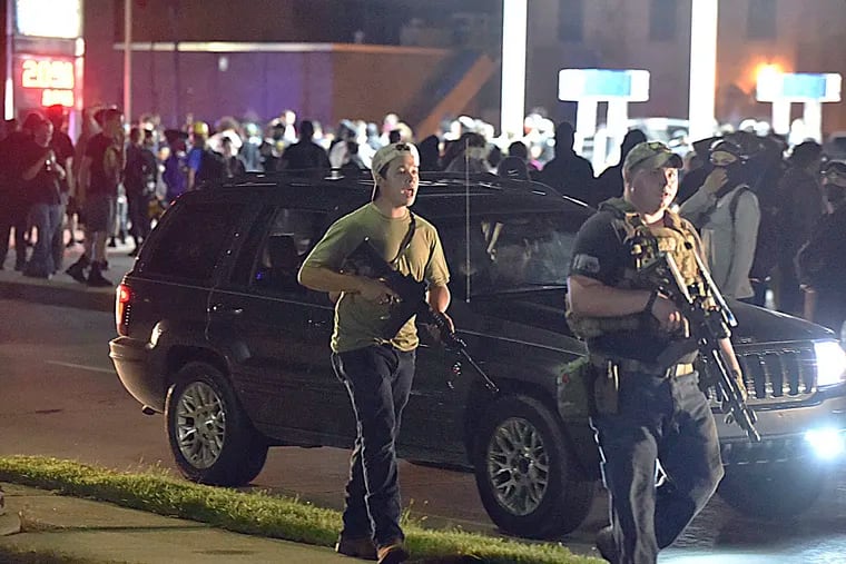 Kyle Rittenhouse, at left in backward cap, walks along Sheridan Road in Kenosha, Wis., at around 11 p.m. Aug. 25, with another armed civilian Tuesday night. Less than an hour later, Rittenhouse, a 17-year-old from Illinois, is accused of shooting three other people, killing two of them, with at least two of the shootings captured on video by onlookers showing Rittenhouse as the shooter. The incident took place after curfew in Kenosha less than 72 hours after demonstrations and riots broke out in the lakeside city following the police shooting of Jacob Blake.