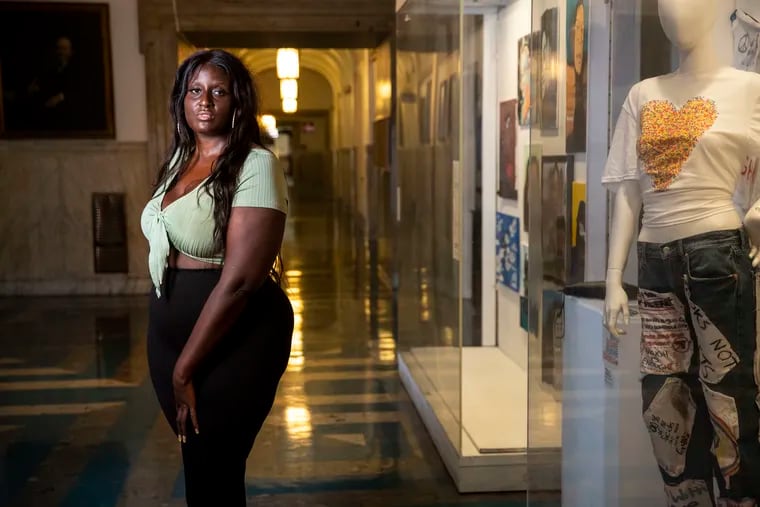 Zarinah Lomax posed Wednesday for a portrait near "We Are Here – Stories and Expressions of Healing" — an art exhibition on the fourth floor of City Hall showcasing the stories of co-victims and survivors of trauma.