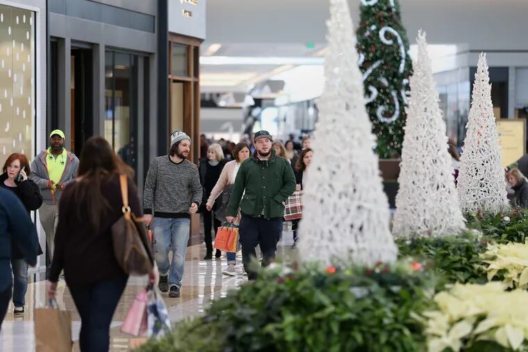Shoppers walk past holiday decorations inside King of Prussia Mall in King of Prussia on Dec 21, 2017.