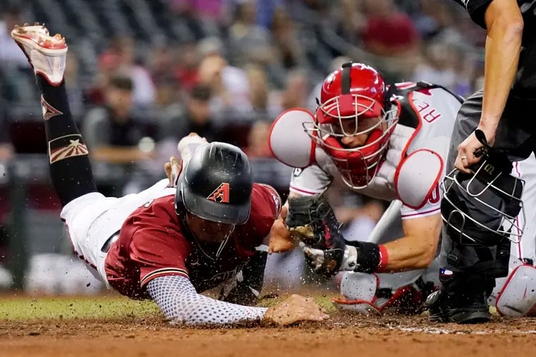 Phillies catcher J.T. Realmuto tags out the Diamondbacks' Josh Rojas on a play at the plate in the second inning Wednesday night in Arizona.