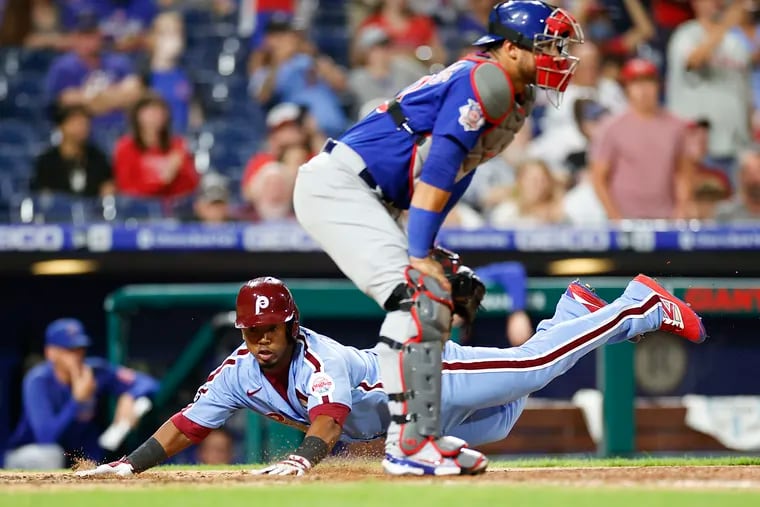 Phillies Jean Segura dives safely past Cubs catcher Willson Contreras to tie the game at 7-7.