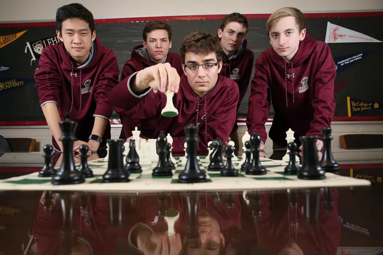 Chess team members (from rear left) Nathaniel O, 15; Ethan Weilheimer, 16; team captain Brecon Hession, 18; and Albert Hatton, 16, stand for a portrait behind senior Yonatan Wiese-Namir, 18, at Abington Senior High School. The four-member team of O, Weilheimer, Wiese-Namir and Hatton won first place in the U1200 division of the U.S. Chess Federation's National High School Championship.