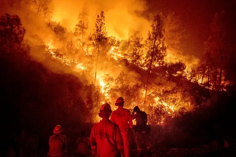 In this Aug. 7, 2018 file photo, firefighters monitor a backfire while battling the Ranch Fire, part of the Mendocino Complex Fire near Ladoga, Calif. Verizon  says it has removed all speed cap restrictions for first responders on the West Coast.