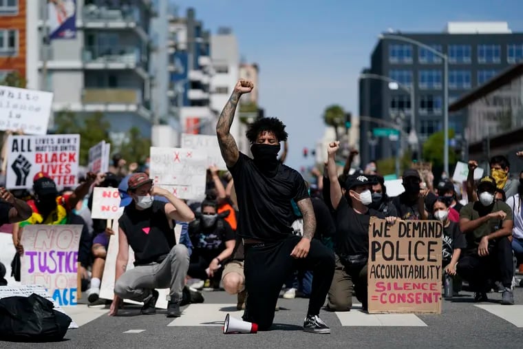 In this May 31 photo, demonstrators kneel in a moment of silence outside the Long Beach Police Department in Long Beach during a protest over the death of George Floyd. Proposed federal legislation that would radically transform the nation's criminal justice system through such changes as eliminating agencies like the Drug Enforcement Administration and the use of federal surveillance technology is set to be unveiled Tuesday by the Movement for Black Lives.