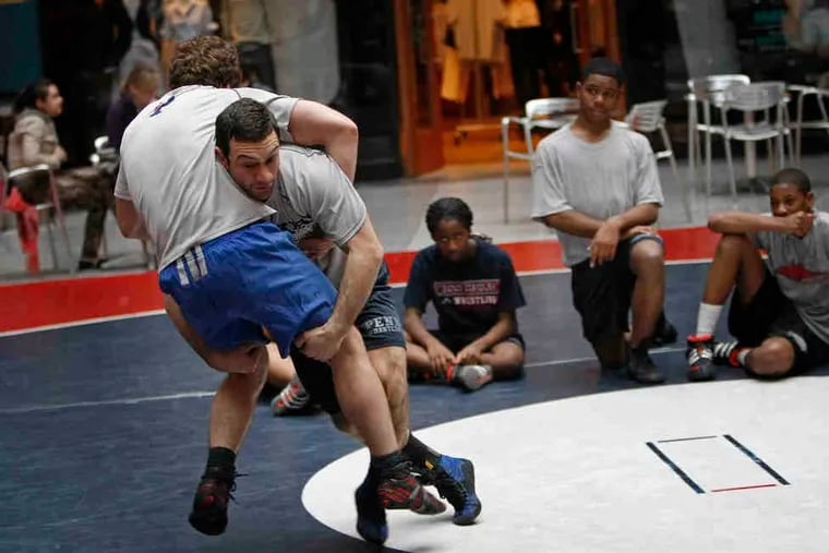 Penn assistant coach Matt Valenti makes a move on Penn's Zack Ellis (left) in a demonstration at the Shops at Liberty Place.