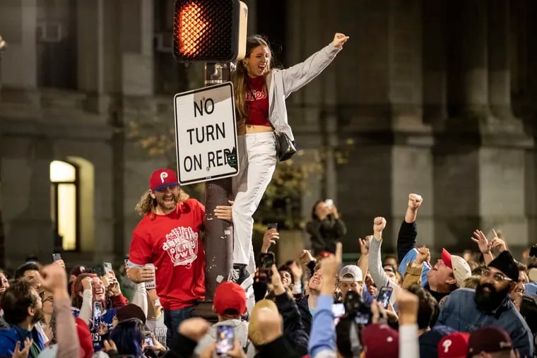 People celebrate the Philadelphia Phillies winning the NLCS with pole climbing on Broad Street south of City Hall in 2022.