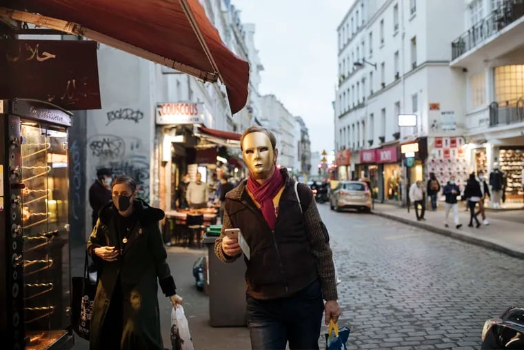 A man wearing a gold mask walked down a street in Paris on Thursday, the final day before France's lockdown.