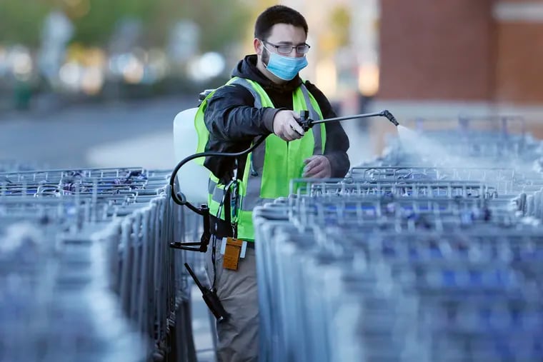 Sam’s Club “cart guy” Billy Mayer uses a sprayer to sanitize about 400 shopping carts at Sam’s Deptford store before it opened to customers on April 11.