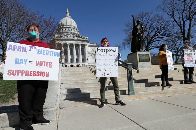 A group with C.O.V.I.D., Citizens Outraged Voters in Danger, protest wearing masks outside the State Capitol during a special session regarding the spring election in Madison, Wis., on Saturday.
