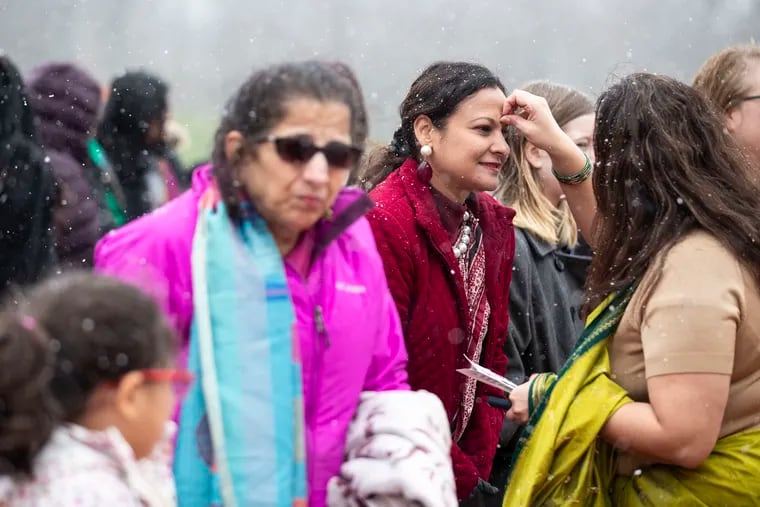 Snow falls as Anu Pasi, of Furlong, places a bindi on Bela Soni, during the first Saree Run at Doylestown Central Park on Sunday.
