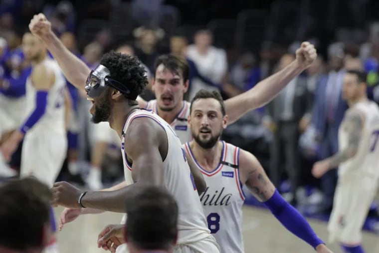 Joel Embiid celebrates his dunk over Aron Baynes in the second quarter as Marco Belinelli (right) and Dario Saric (center) rush to him.