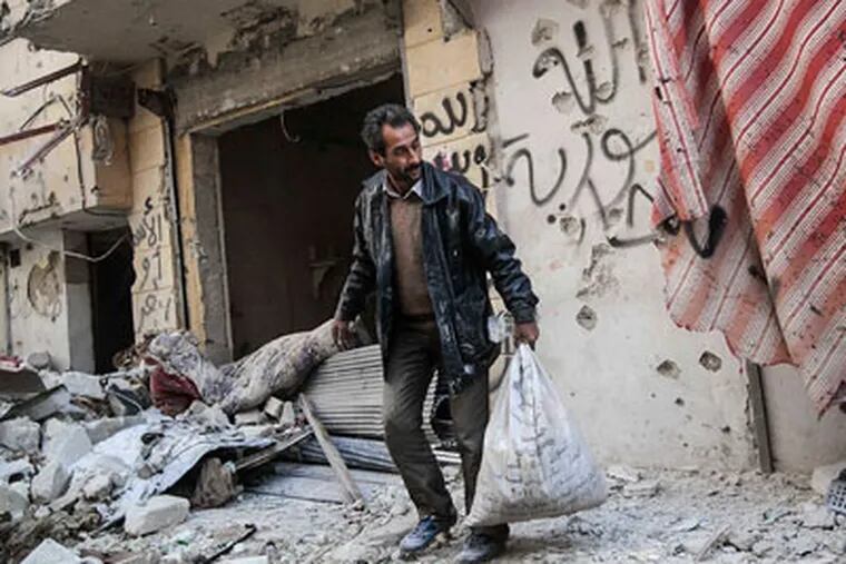 In this Sunday, Dec. 2, 2012 photo, a man collects his belongings after his home was damaged due to heavy fighting between Free Syrian Army fighters and government forces in Aleppo, Syria. (AP Photo/Narciso Contreras)