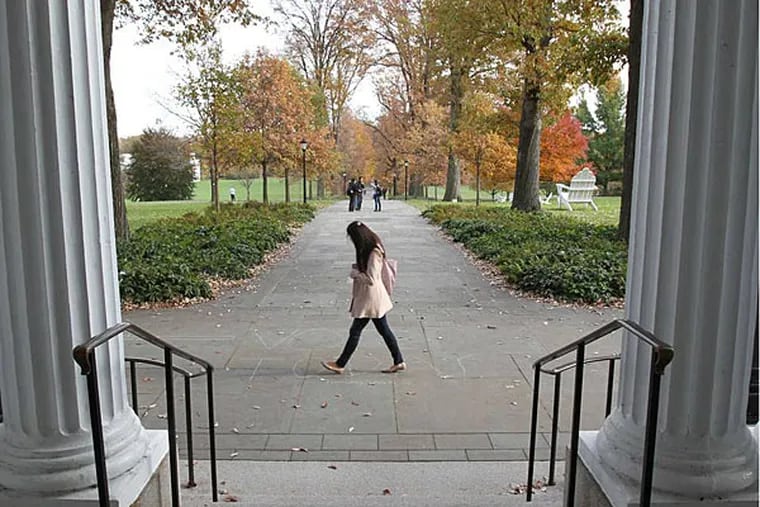 A pedestrian crosses Magill Walk on Swarthmore College  on Nov. 5, 2013.  The columns of Parrish Hall, which is the original Swarthmore College building, built in 1869 and rebuilt after a fire in 1881, are in the foreground. ( CHARLES FOX / Staff Photographer )