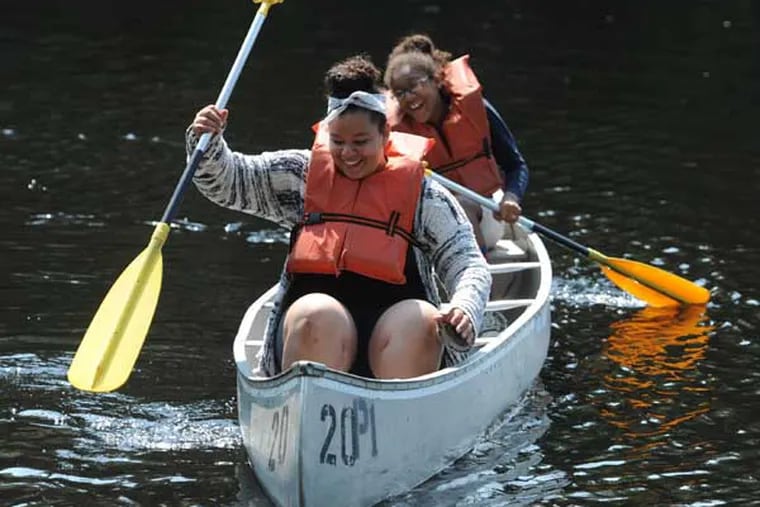 Destiny Colon (front), 13, and Arianna Boyer, 12, both from Camden, push off from shore in a canoe on Lummy Lake in Belleplain State Forest, Woodbine, NJ, July 31, 2014.  The girls are part of a group of 150 kids from Camden participating in the Rowan University CHAMP program, which included an overnight in tents in the forest and recreation time to swim and canoe in the lake before going home.  ( CLEM MURRAY / Staff Photographer )