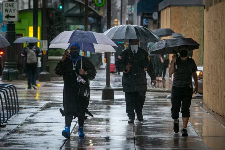 Pedestrians walking in the rain along Market Street near 12th Street.