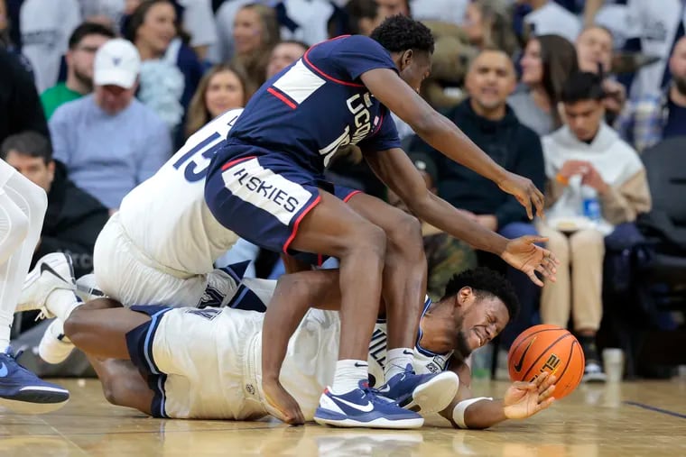 Hassan Diarra of UConn and TJ Bamba of Villanova go after a loose ball during the second half Saturday at the Wells Fargo Center.