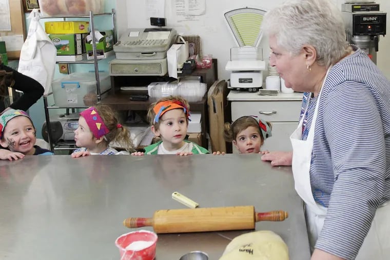 Roz Bratt prepares to make Hamantaschen cookies at her Jewish bakery, Homemade Goodies by Roz, in Philadelphia on March 13, 2014. Students from the Center City Jewish Preschool watch her work during a recent visit. ( DAVID MAIALETTI / Staff Photographer )