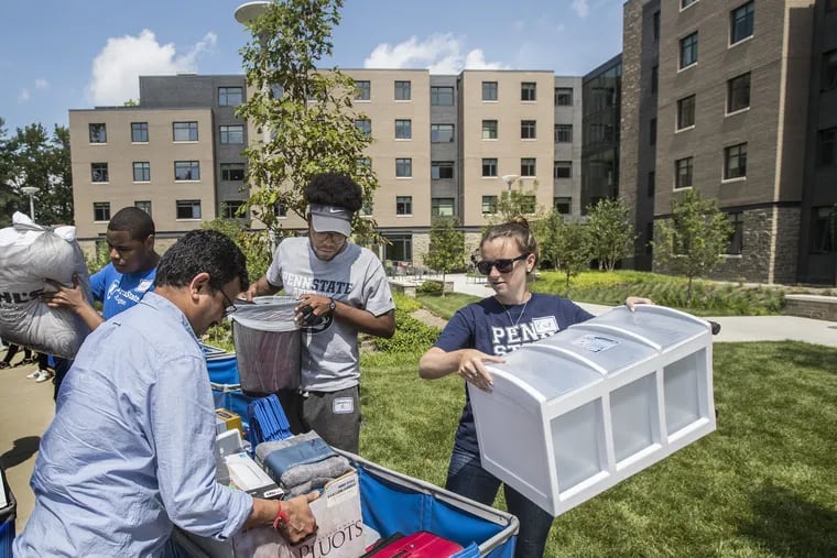 Kaitlyn Condon, right, a Penn State Abington staffer, helps a student's family load up the blue carts so they can be wheeled into the new residence hall behind them on Wednesday. Penn State Abington will open its first dorm this fall, part of a new effort to boost retention and accommodate students who want to live on campus, as University Park becomes increasingly crowded. Nearby Penn State Brandywine also is opening its first dorm. 08/16/2017 MICHAEL BRYANT / Staff Photographer