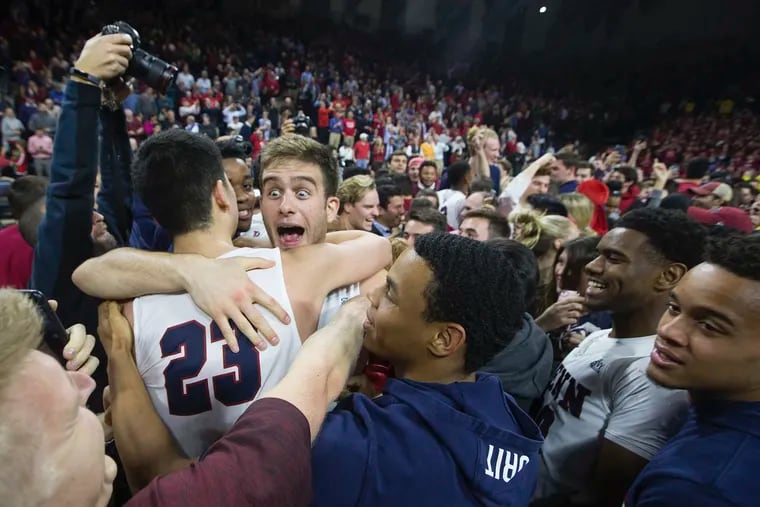 Penn's Max Rothschild (center) hugs teammate Michael Wang as they celebrate a 78-75 victory over Villanova at the Palestra on Dec. 11, 2018.