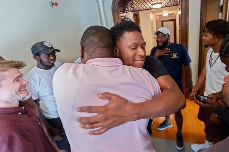 Nasir Lee, center, gets a hug from Tony Thomas, left, the field and training coordinator for the Healers program. The Healers, a group of young men of color, who have all experienced trauma - gun violence, abuse, poverty - who ate going through a 9 week boot camp to become peer workers to help people like themselves. When they graduate, it will be their job to meet victims of gun violence at their hospital beds