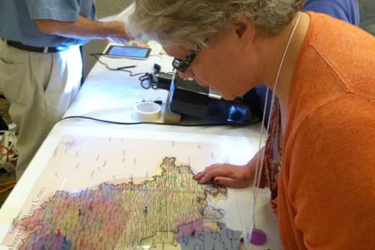 Ruth Bogutz of Cherry Hill searches for the birthplace of her father, Henry Schreibstein, on a map of Europe at Sunday's Jewish Genealogy Fair at Temple Beth Shalom in Cherry Hill. (Kevin Riordan)