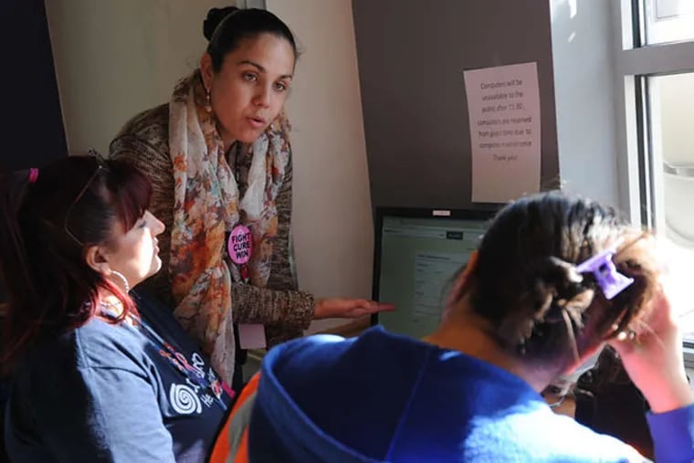 At Congreso Education & Training Center in North Philadelphia, application counselor Elizabeth Rosario (standing) helps a woman (right) who wants to apply for health-care coverage online. The group serves 14,000 people in the city's Latino community.