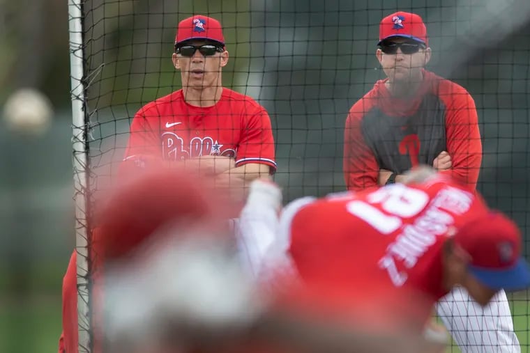 Phillies manager Joe Girardi (left) and former closer Brad Lidge watch the team's pitchers during spring training.