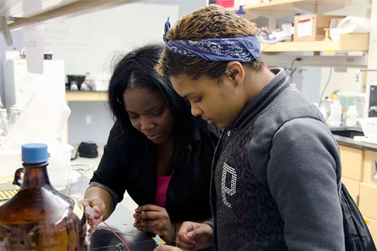 Latrisha Robinson (left) and K'Yanna Wesley of Woodbury High School experiment with the chemistry of colors at Rowan University's Science Day. Six high schools participated in the event. Story, B4. RACHEL WISNIEWSKI / Staff Photographer