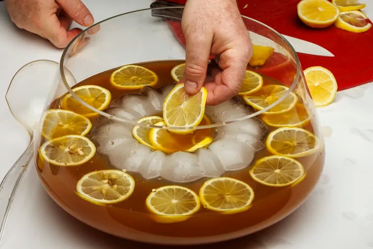 Placing lemon slices into a holiday punch -- a “Philly-centric version built around local spirits.”