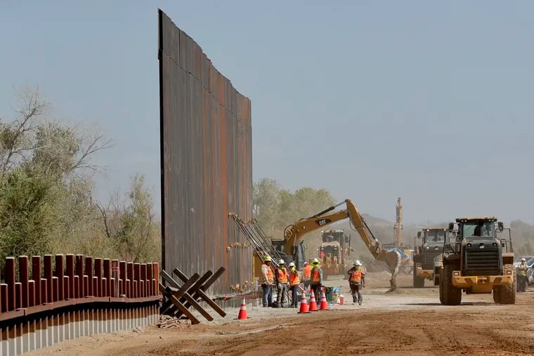 Government contractors erect a section of Pentagon-funded border wall along the Colorado River, Tuesday, Sept. 10, 2019 in Yuma, Ariz. The 30-foot high wall replaces a five-mile section of Normandy barrier and post-n-beam fencing, shown at left, along the the International border that separates Mexico and the United States. Construction began as federal officials revealed a list of Defense Department projects to be cut to pay for President Donald Trump's wall. (AP Photo/Matt York)