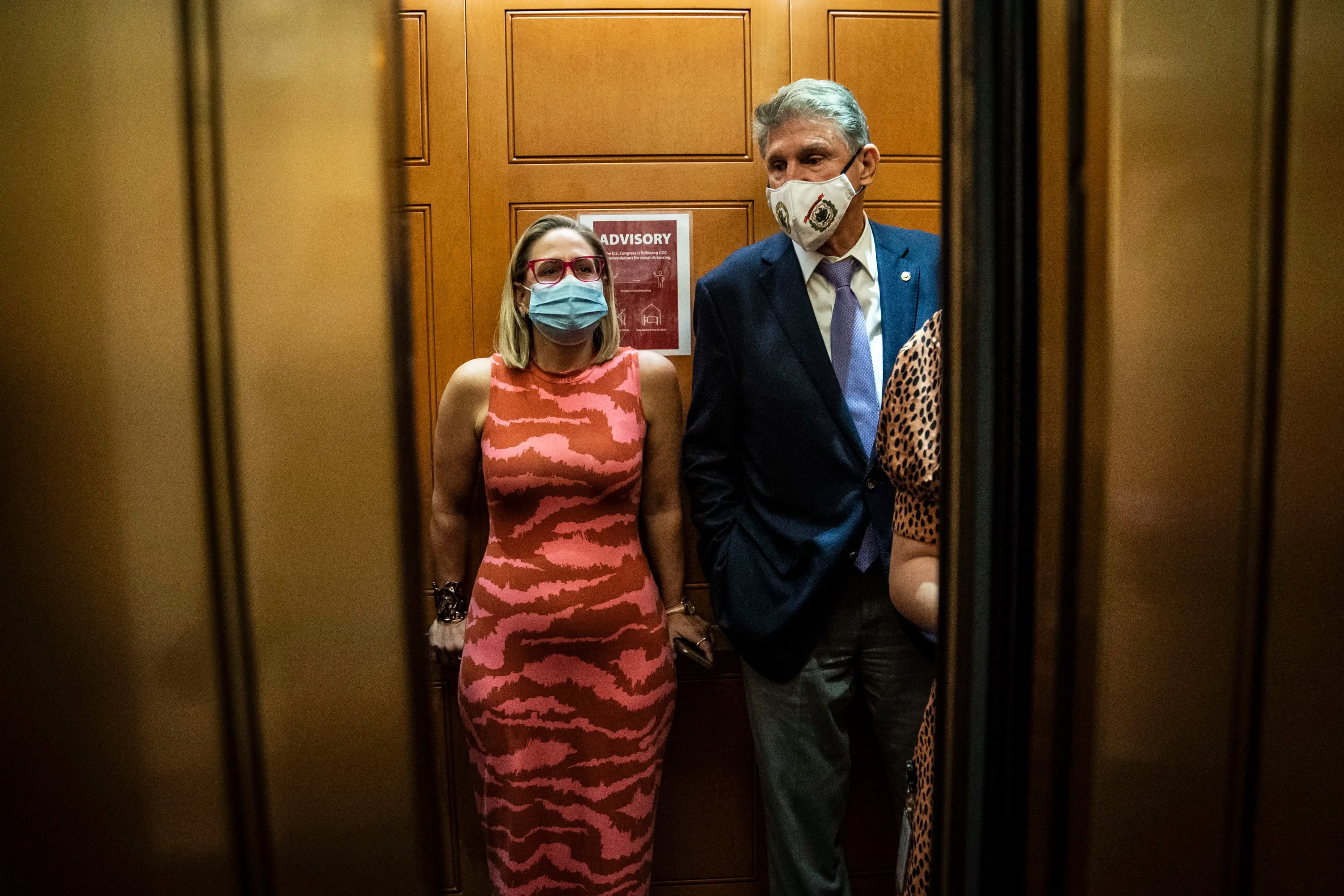 Democratic Sens. Kyrsten Sinema of Arizona and Joe Manchin of West Virginia board an elevator after a private meeting between the two of them on Sept. 30 on Capitol Hill.