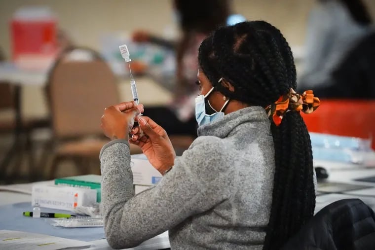 A health worker prepares a dose of the vaccine during a vaccination clinic at the Grand Yesha Ballroom, in South Philadelphia, Wednesday, March 17, 2021.