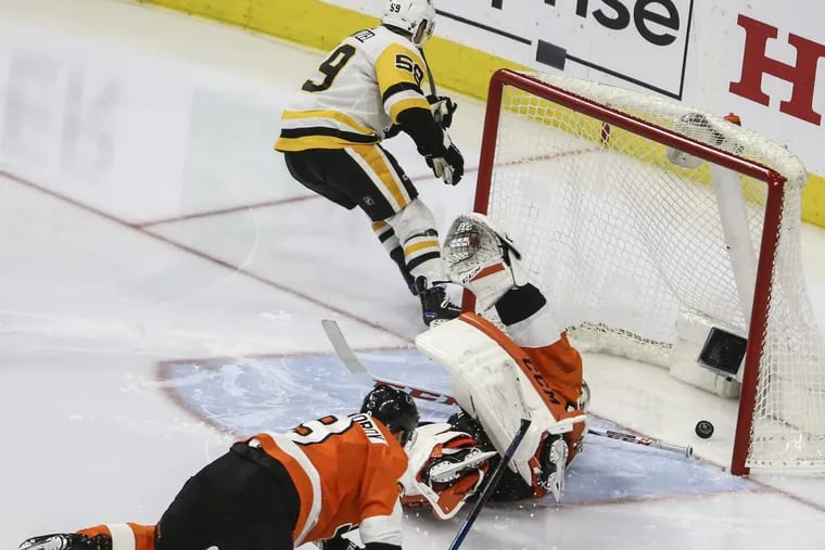 Ivan Provorov and goaltender Michal Neuvirth are left sprawled on the ice as Jake Guentzel celebrates one of the four goals he scored on Sunday night.