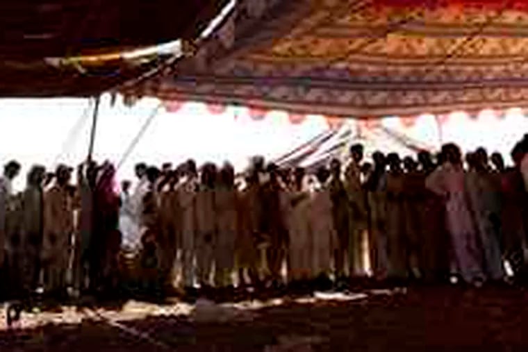 Displaced men waited yesterday at a refugee camp near Peshawar for rugs and buckets. In northwest Pakistan, troops faced a tough fight for the city of Mingora.