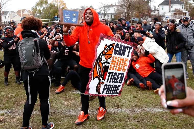 Woodrow Wilson coach Preston Brown holds the trophy and a poster after the Tigers won the South Jersey Group 3 football championship Saturday, Nov. 23, 2019 in Camden. The host Tigers defeated Somerville, 54-30, in the final.