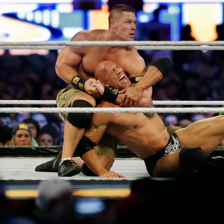 Wrestler John Cena, top, chokes Dwayne "The Rock" Johnson at a Wrestlemania event on April 7, 2013, in East Rutherford, N.J. It is a name that has become almost synonymous with professional wrestling but its bearer, Dwayne Johnson, has never legally owned "The Rock." (AP Photo/Mel Evans, File)