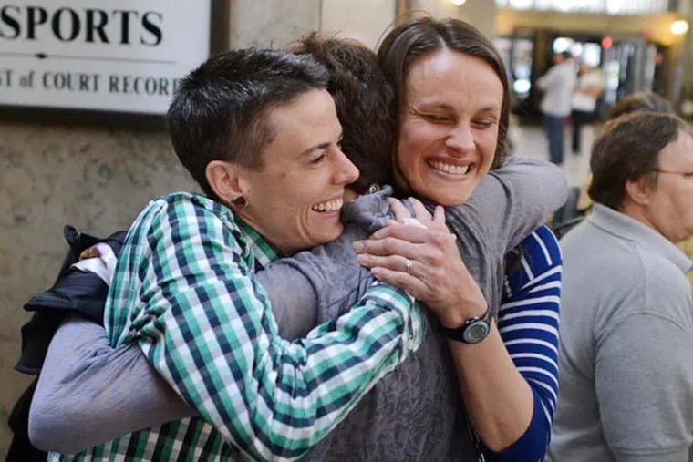 Jess Garrity, left, and Pamela VanHaitsma, right, hug their friend Jamie Phillips, enter, while standing first in line to apply for a marriage license inside the City-County Building in downtown Pittsburgh. (Michael Henninger/Pittsburgh Post-Gazette/TNS)
