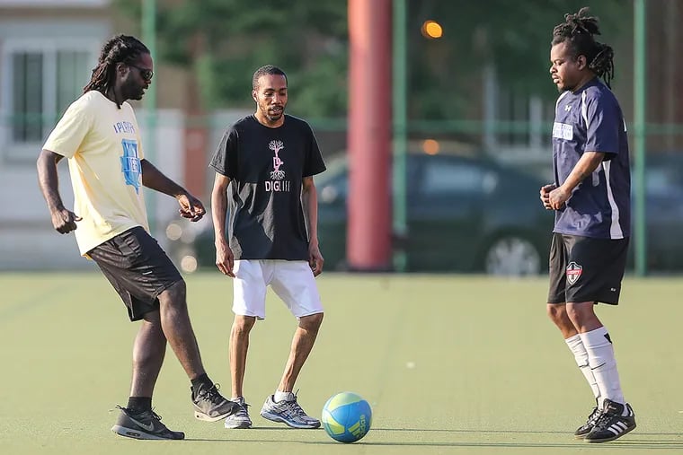 Coach Tom Laws kicks the ball around with players Donte Jackson and Mark Walker.