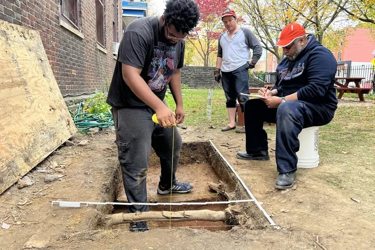 Faruq Adger (left), a Penn undergraduate and work study student with the Heritage West community archaeology project, maps out an excavation unit in front of the Community Education Center, along with Robert Bryant (center), a graduate student at Penn, and Erik Weaver (right), a community member and volunteer excavator. The project aims to learn more about West Philly's Black Bottom, a predominantly Black neighborhood that was cleared to create University City.