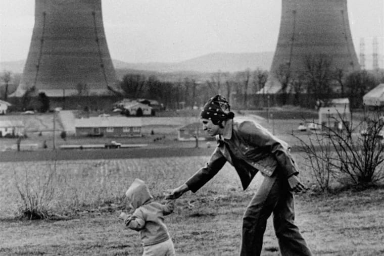 Mrs. Julie Sipling takes her daughter Debbie, 13 months, for a walk outside her home near cooling towers of the Metropolitan Edison Three Mile Island nuclear plant Wednesday afternoon, March 29, 1979, located near Harrisburg, Pa. (AP Photo/Harrisburg Patriot-News, Martha Cooper)