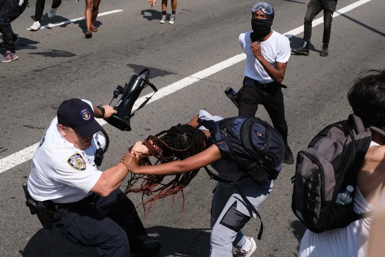 Black Lives Matter protesters scuffle with an NYPD officer on the Brooklyn Bridge in New York during a demonstration Wednesday. Several New York City police officers were attacked and injured during the protest, police said, and more than a dozen people were arrested.