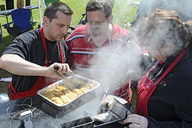 Checking their chicken are team ZBQ’s Mark Zonfrillo (left), brother Paul, and sister-in-law Ann, lost in the smoke. (CLEM MURRAY / Staff Photographer)
