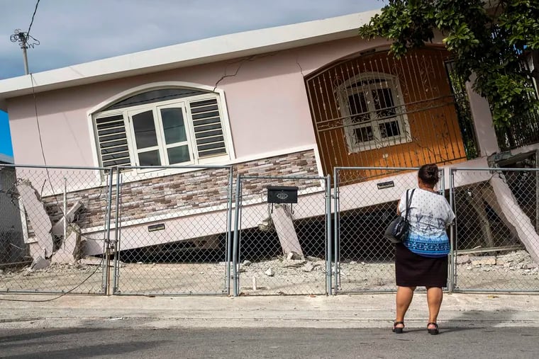 A woman stands in front of a house damaged by a 5.8 earthquake in Guanica, Puerto Rico on Monday, Jan. 6, 2020. The quake toppled some structures and caused power outages and small landslides, but there were no reports of casualties, the U.S. Geological Survey said. (Ricardo Arduengo/AFP/Getty Images/TNS)